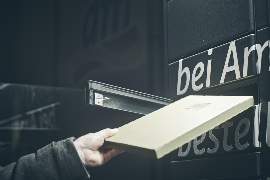 a-person-holding-a-box-in-front-of-a-sign-ofjp5ee57xs